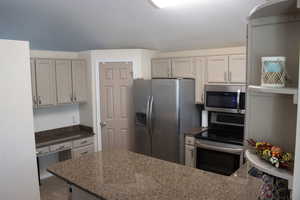 Kitchen featuring stainless steel appliances, dark stone countertops, and a peninsula