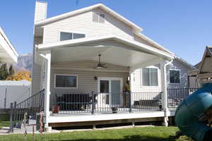 Rear view of house with ceiling fan, a deck, and a chimney