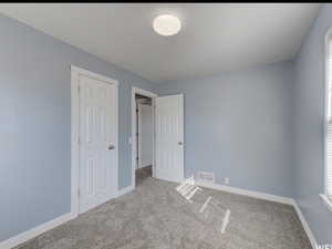 Unfurnished bedroom featuring light carpet and baseboards