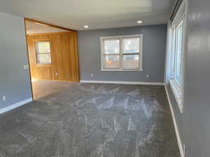 Unfurnished room featuring wooden walls, carpet flooring, and recessed lighting