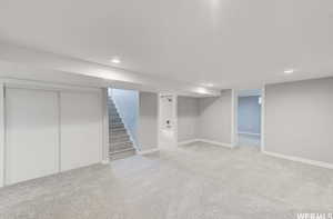 Finished basement with light colored carpet, stairway, and recessed lighting