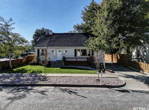 View of front of house with driveway, roof with shingles, and a deck