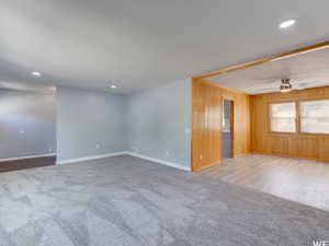 Spare room featuring light colored carpet, wooden walls, and recessed lighting