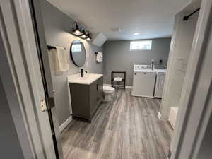 Full bathroom featuring vanity, wood finished floors, separate washer and dryer, and a shower