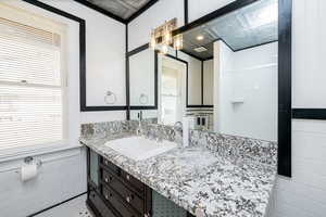 Bathroom with tile walls, vanity, wainscoting, and a chandelier