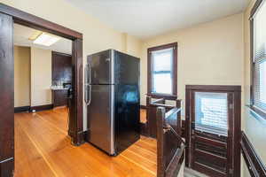 Kitchen featuring freestanding refrigerator, light wood finished floors, and dark brown cabinets