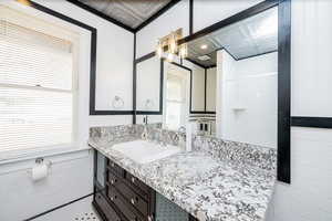 Full bath with tile walls, healthy amount of natural light, vanity, and wainscoting