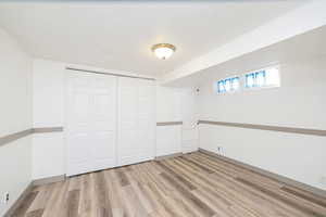 Unfurnished bedroom with a textured ceiling, light wood-style floors, and a closet