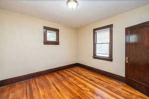 Empty room featuring hardwood / wood-style floors, plenty of natural light, and a textured ceiling