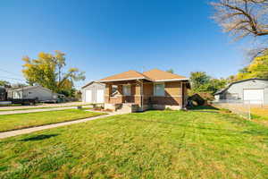Bungalow-style home with brick siding, an outdoor structure, a garage, and a porch