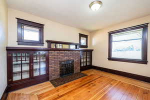 Unfurnished living room featuring hardwood / wood-style flooring, a brick fireplace, and a textured ceiling