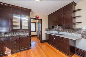 Kitchen with decorative backsplash, open shelves, dark brown cabinetry, light wood-style flooring, and a textured ceiling