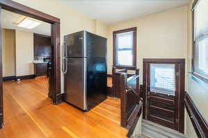 Kitchen featuring freestanding refrigerator, light wood-style floors, and dark brown cabinets