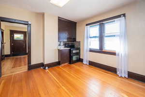 Kitchen with dark brown cabinetry, light wood-style flooring, range with two ovens, decorative backsplash, and a textured ceiling