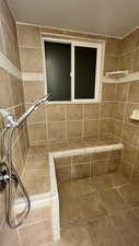 Full bath featuring tiled shower and tile patterned flooring