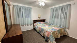 Carpeted bedroom featuring ceiling fan and baseboards