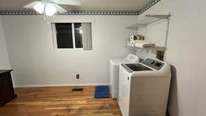 Laundry room with light wood-type flooring, a ceiling fan, and washing machine and dryer