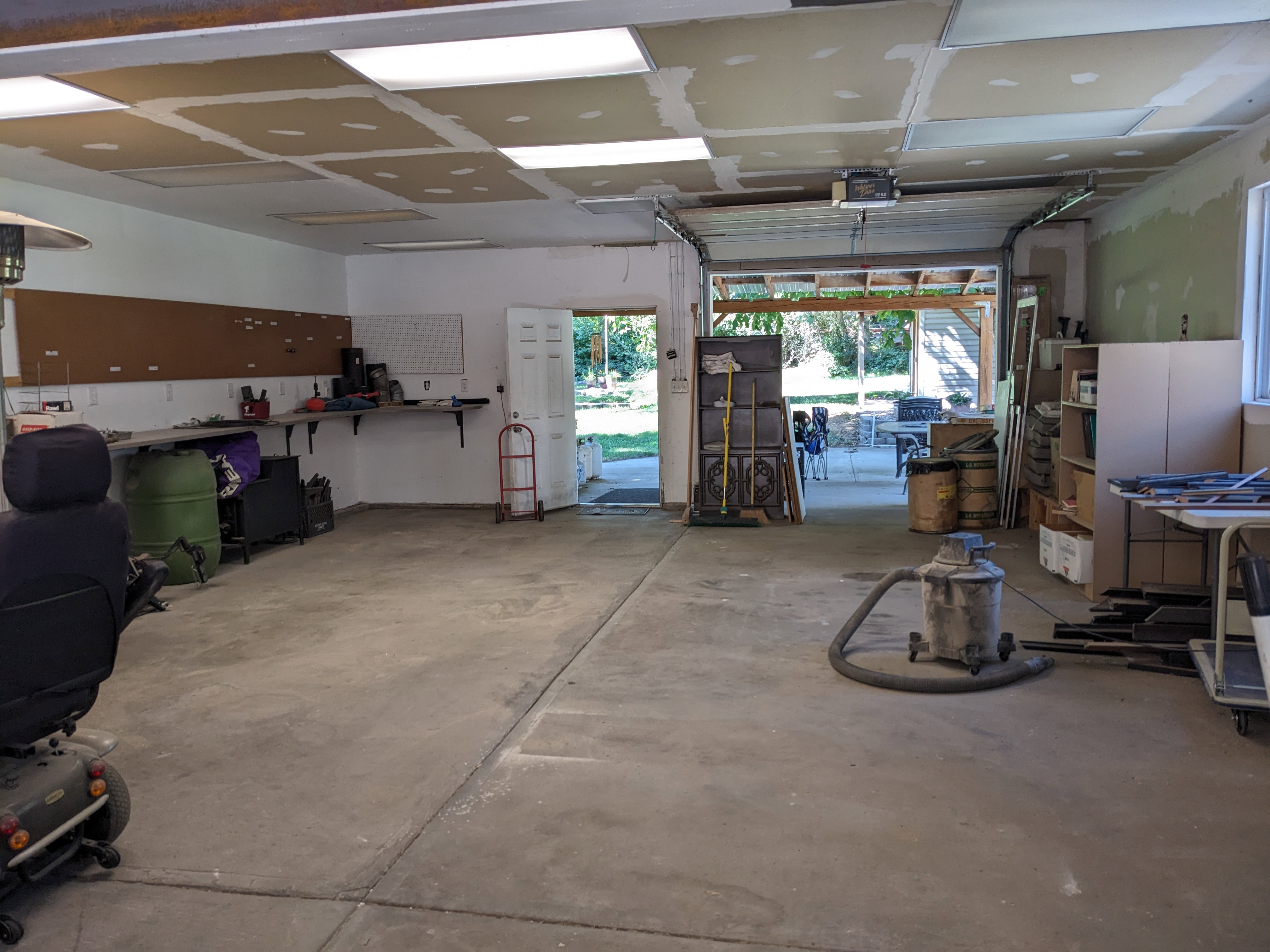 Garage with a garage door opener and a workshop area looking out the back doors.