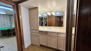 Bathroom featuring vanity, a textured ceiling, and wooden walls