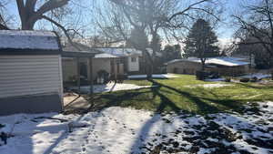 Snowy yard featuring a patio area and a lawn
