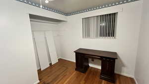 Unfurnished bedroom with dark wood-style floors and a closet