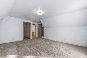 Primary Bedroom with lofted ceiling, carpet, and a textured ceiling