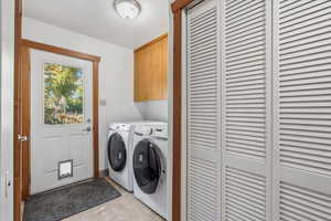 Laundry room with light tile patterned floors, independent washer and dryer, and cabinet space