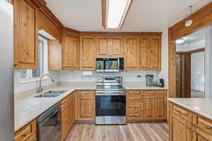 Kitchen with appliances with stainless steel finishes, light wood-type flooring, plenty of natural light, and brown cabinetry