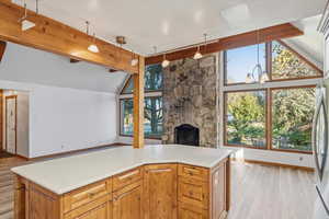 Kitchen with a fireplace, light wood-style floors, freestanding refrigerator, brown cabinetry, and light countertops