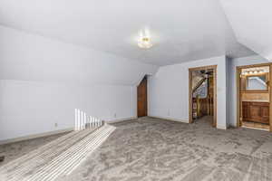 Primary Bedroom featuring light carpet, lofted ceiling, and a textured ceiling