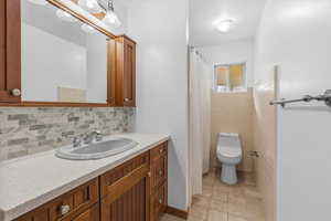 Bathroom with vanity, light tile patterned floors, curtained shower, and tasteful backsplash