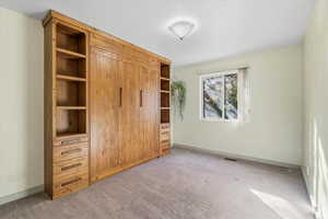 Unfurnished bedroom with light carpet and baseboards