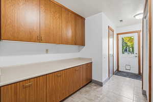 Laundry featuring brown cabinetry, light countertops, and light tile patterned floors