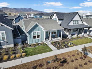 View of front of house with a shingled roof, board and batten siding, covered porch, a residential view, and a mountain view