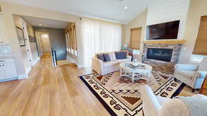 Living room with woven wood finished floors, a linear fireplace, high vaulted ceiling, , metal railing, and recessed lighting