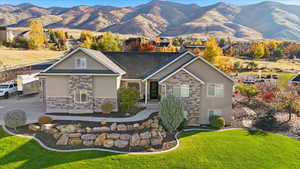 View of front of property featuring stucco siding, stone siding, a mountain view, and a front yard