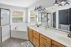 Bathroom featuring a stall shower, a bath, double vanity, and dark tile patterned floors