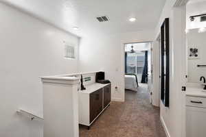 Hall featuring dark colored carpet and a textured ceiling