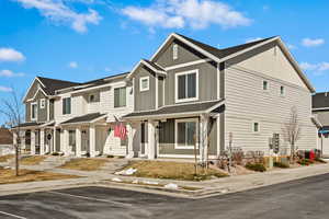View of front facade featuring covered porch, roof with shingles, board and batten siding, and a residential view