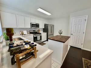 Kitchen featuring butcher block counters, white cabinets, stainless steel appliances, and a kitchen island