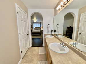 Full bath featuring double vanity, connected bathroom, and light tile patterned floors