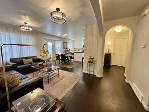 Living area with dark wood finished floors, arched walkways, and recessed lighting