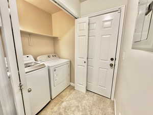 Washroom featuring washing machine and clothes dryer and light tile patterned floors
