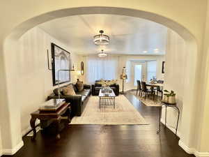Living room featuring arched walkways and dark wood-style floors