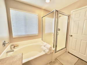 Full bath featuring a stall shower, a bath, and light tile patterned floors