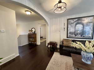 Living room featuring wood finished floors, a chandelier, and arched walkways