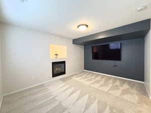 Finished basement featuring light colored carpet and a glass covered fireplace