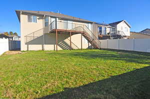 Rear view of property featuring a deck, stairway, and a fenced backyard