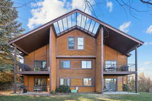Back of house featuring a patio, a lawn, and a balcony
