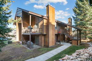 Rear view of house with stairs, a chimney, and a balcony
